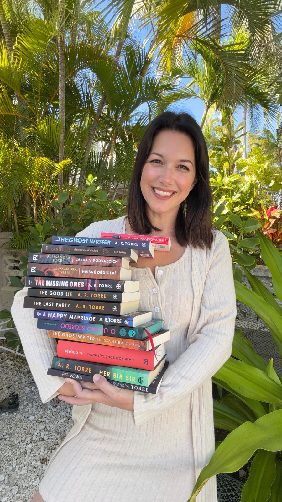 Alessandra Torre holding a stack of her published books